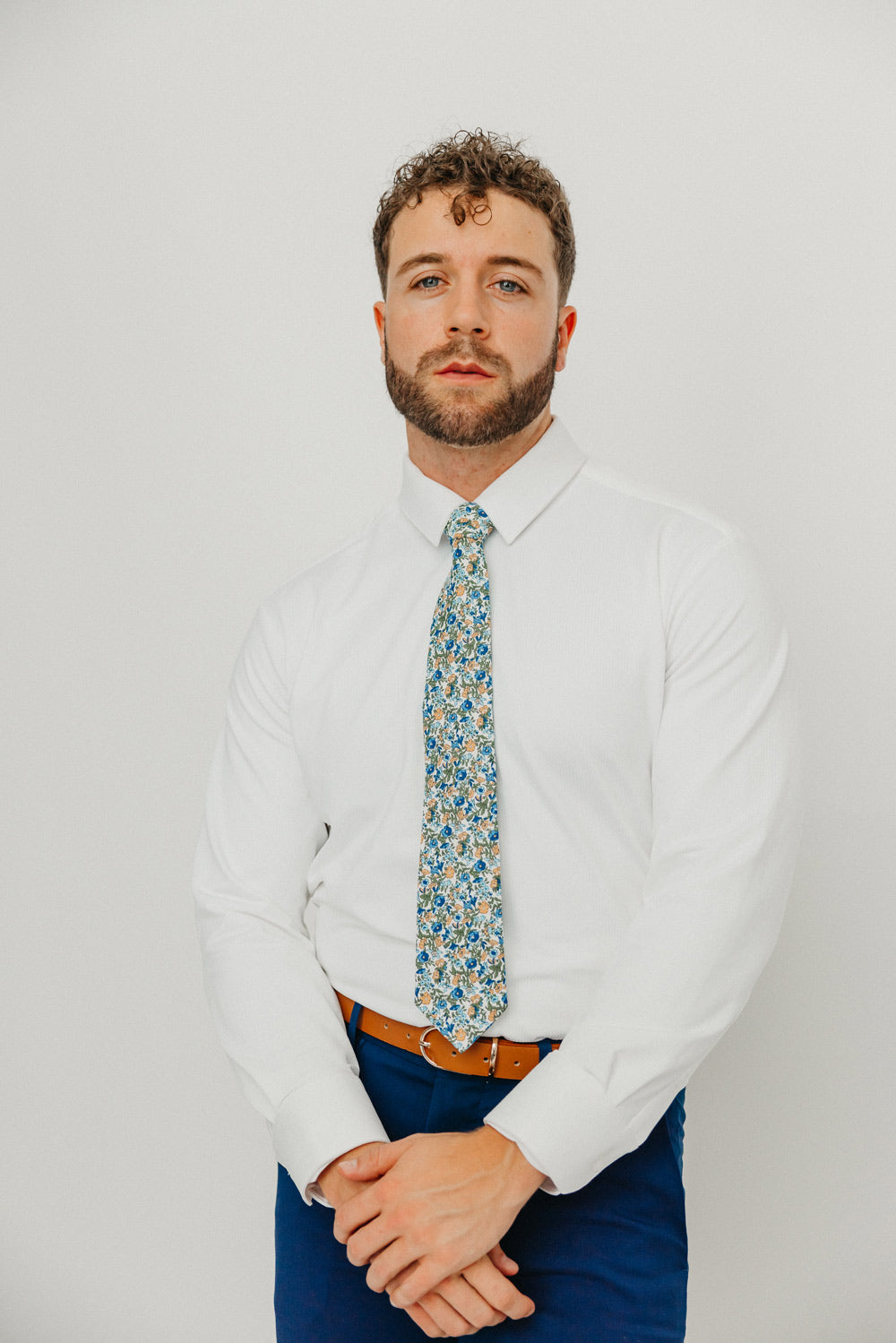 Alpine Blum tie worn with a white shirt, brown belt and blue pants.