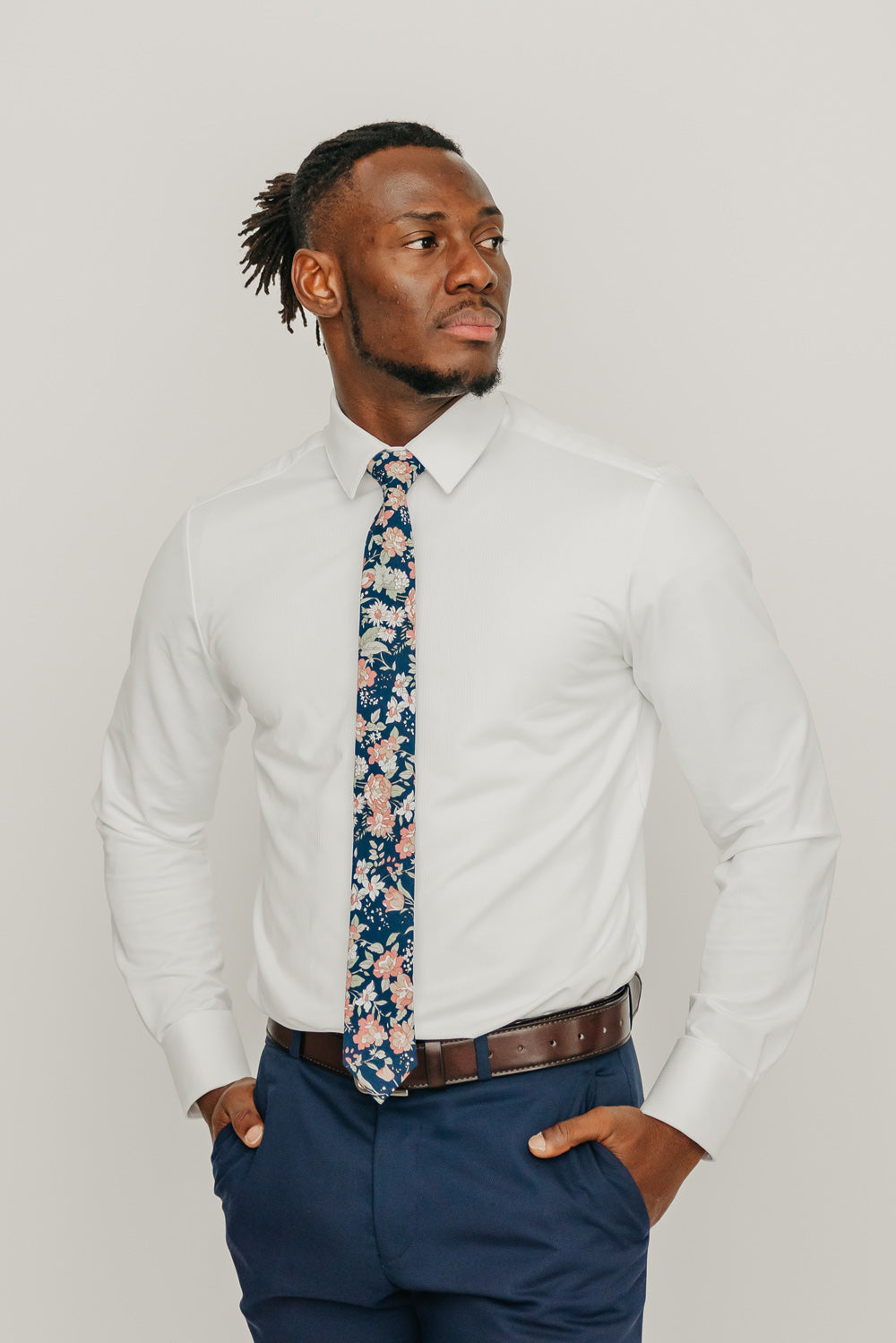 Lotus tie worn with a white shirt, brown belt and blue pants.