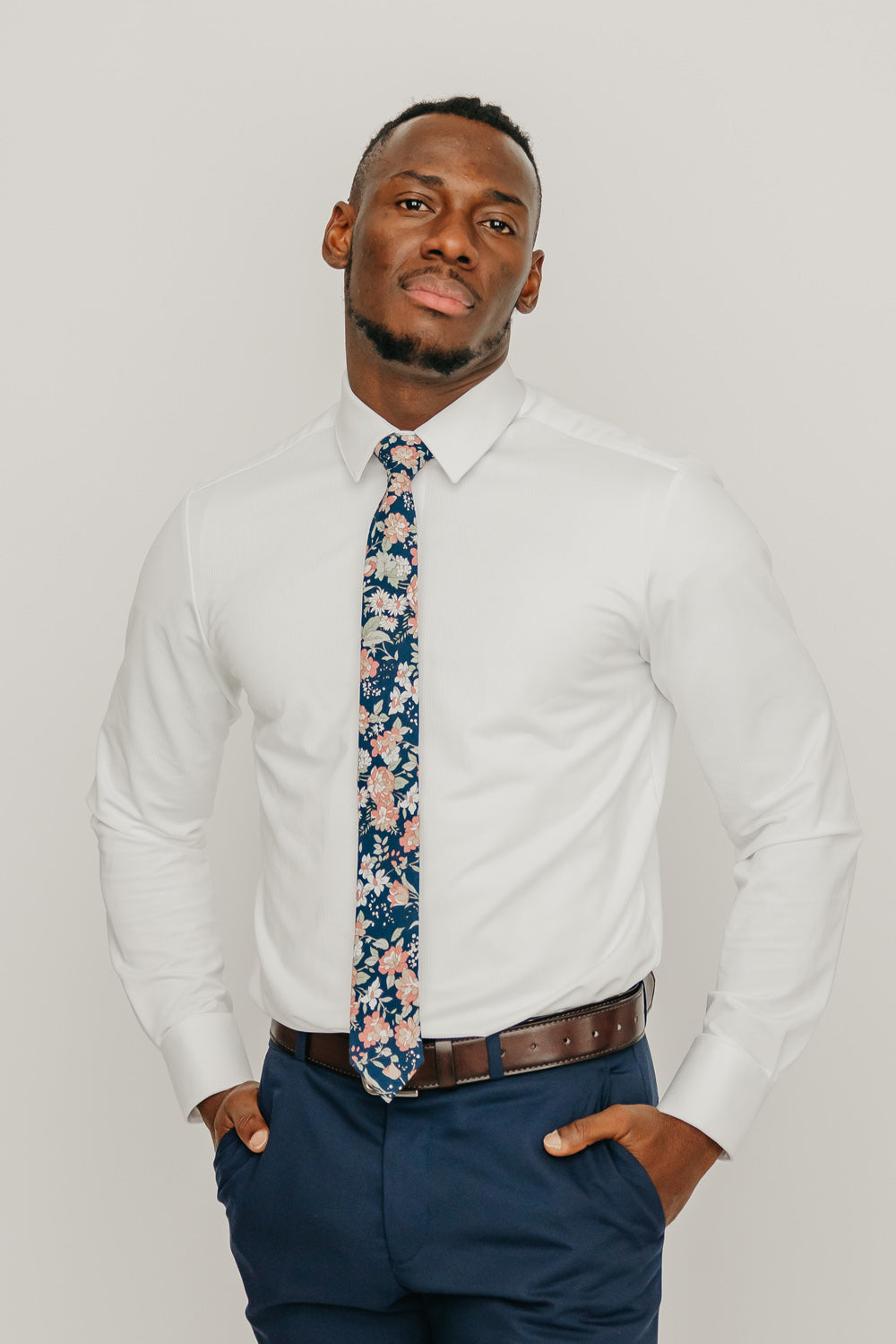 Lotus tie worn with a white shirt, brown belt and blue pants.