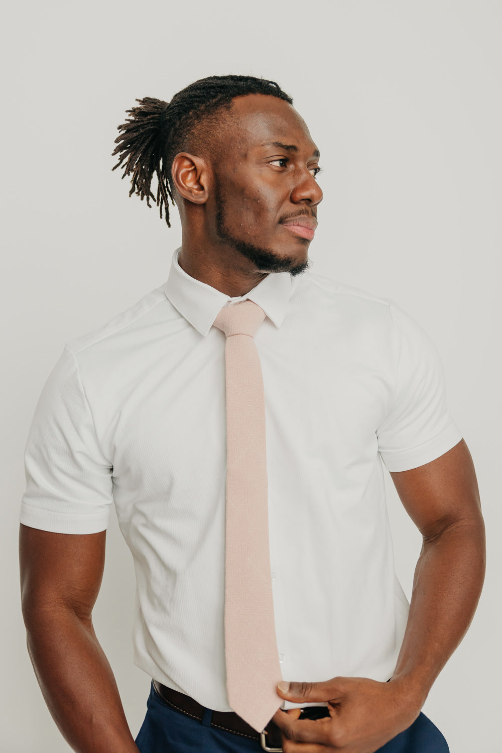 Mauve tie worn with a white shirt, brown belt and blue pants.