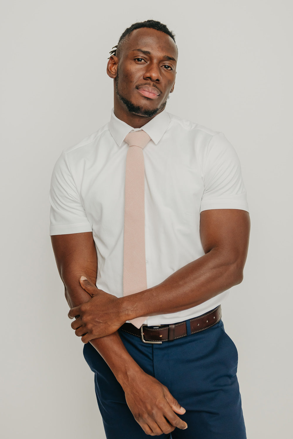 Mauve tie worn with a white shirt, brown belt and blue pants.