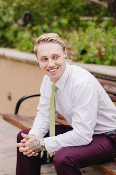 Moss tie worn with a white shirt and plum purple suit pants.