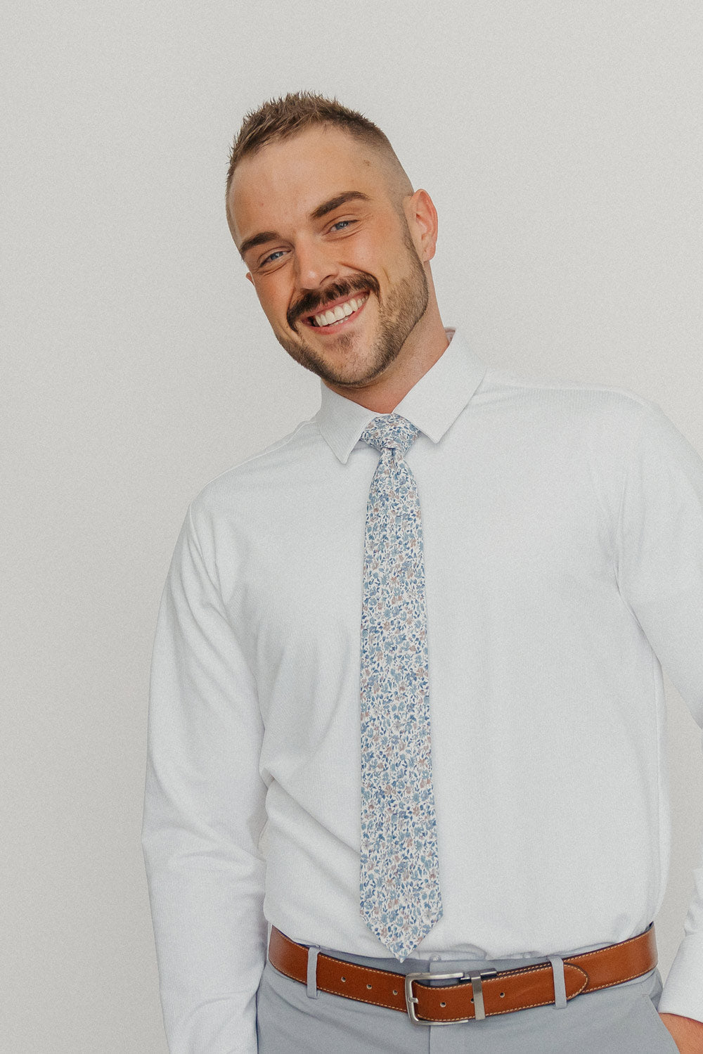 Scorpion Grass tie worn with a white shirt, brown belt and gray pants.