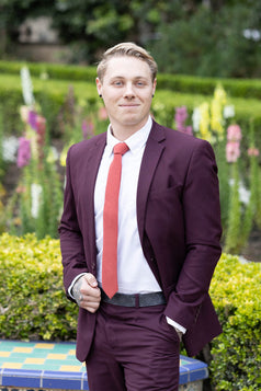 Spice necktie worn with a white shirt and plum purple suit. 