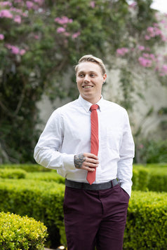 Spice necktie worn with a white shirt and plum purple suit pants.