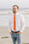 Tangerine tie worn with a white shirt and blue pants.