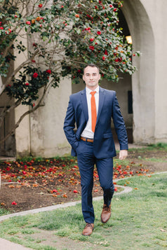 Tangerine tie worn with a white shirt and blue suit. 