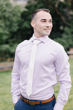 White tie worn with a light purple suit and blue suit pants.