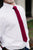 Wine necktie worn with a white shirt and blue pants. 