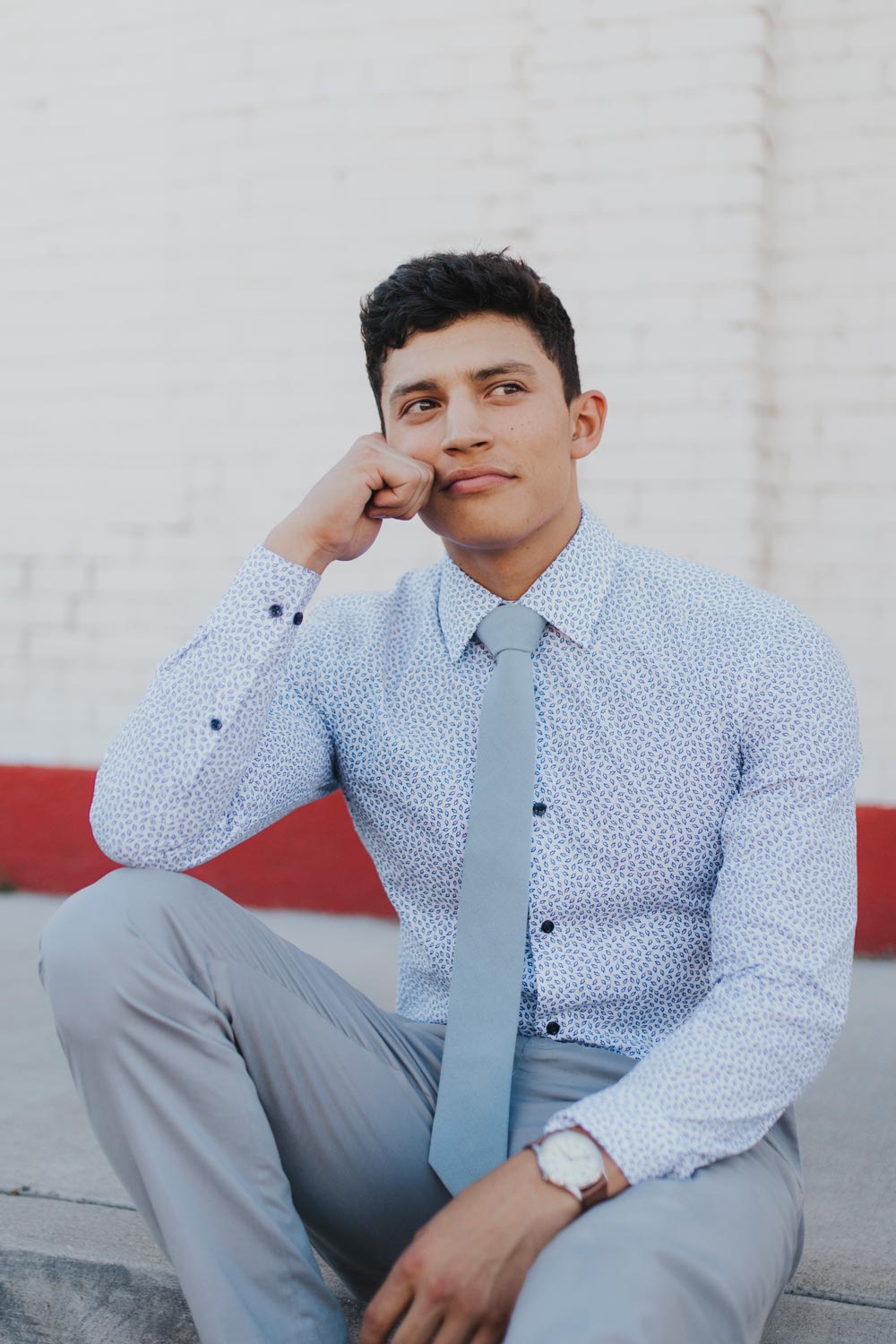 Dusty tie worn with a blue patterned shirt, brown belt and light gray pants.