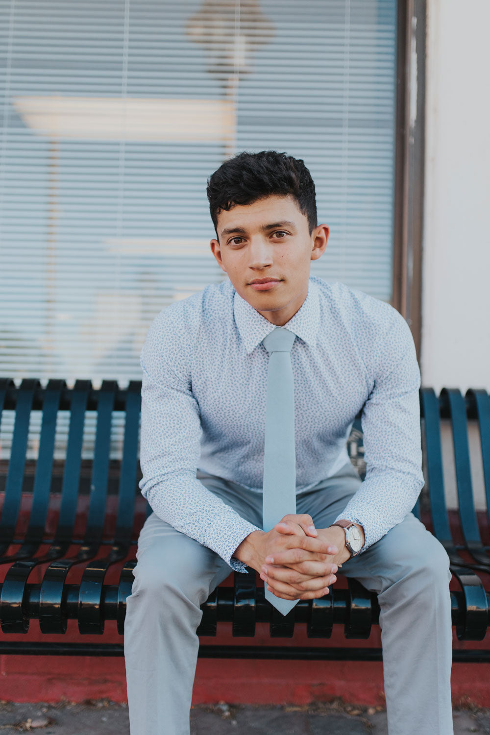 Dusty tie worn with a blue patterned shirt, brown belt and light gray pants.