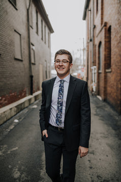 Lilac tie worn with a white shirt and dark gray suit.