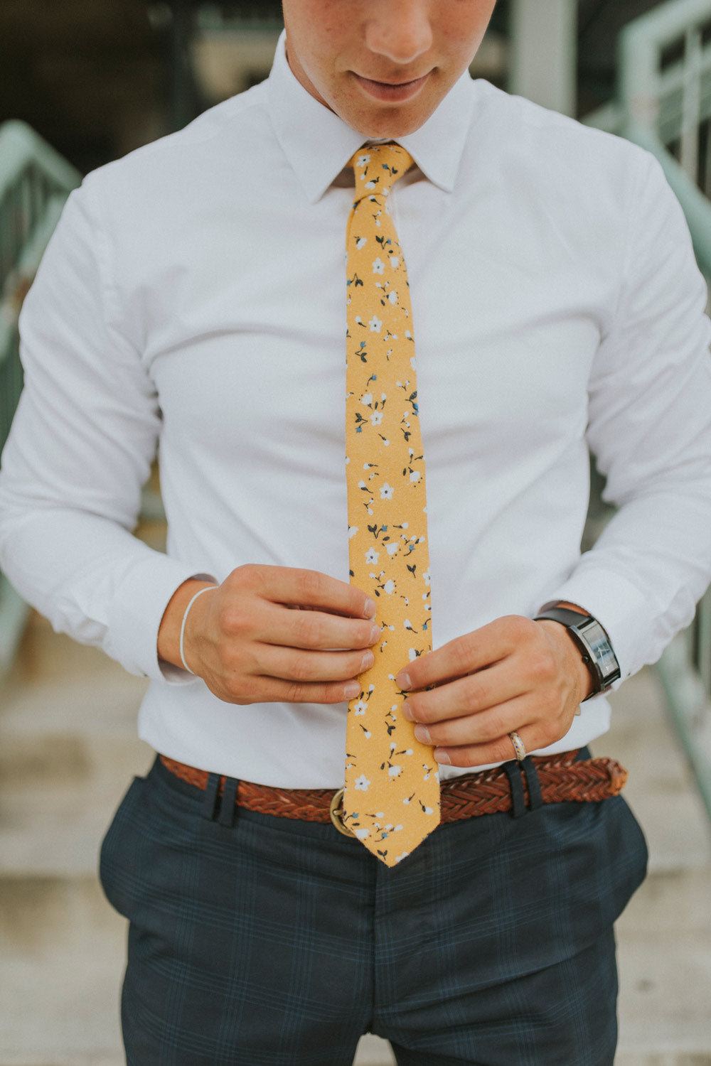 Marigold tie worn with a white shirt, brown belt and gray patterned pants.