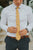 Marigold tie worn with a white shirt, brown belt and gray patterned pants.