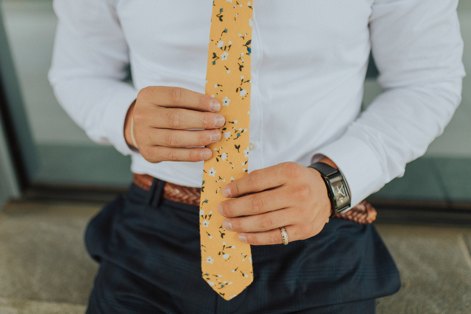 Marigold tie worn with a white shirt, brown belt and gray patterned pants.