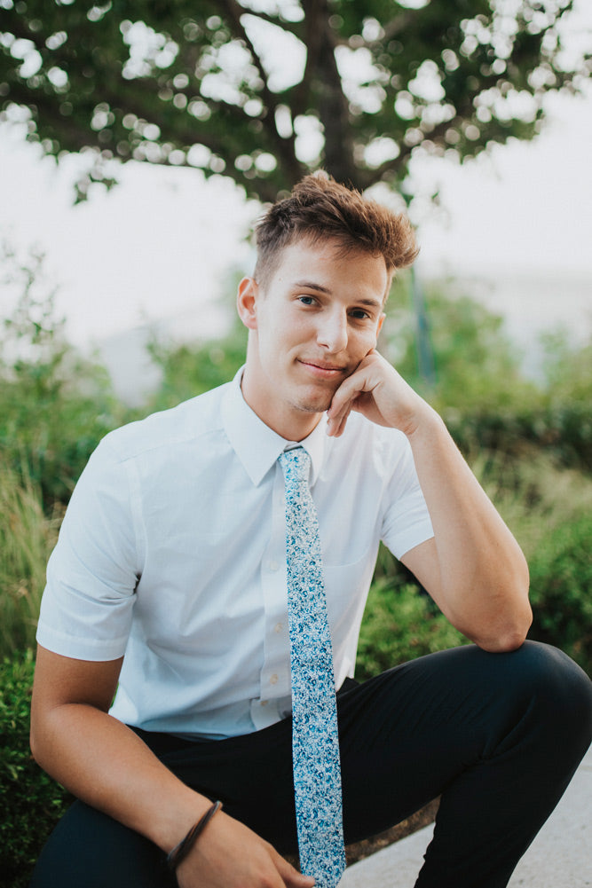 Powder tie worn with a white shirt and navy blue pants.