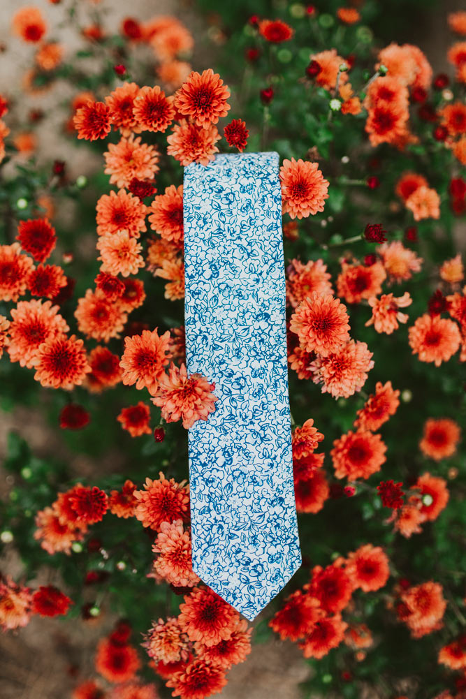 Powder tie laying in some red and orange flowers.