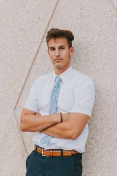 Powder tie worn with a white shirt, brown belt and navy blue pants.