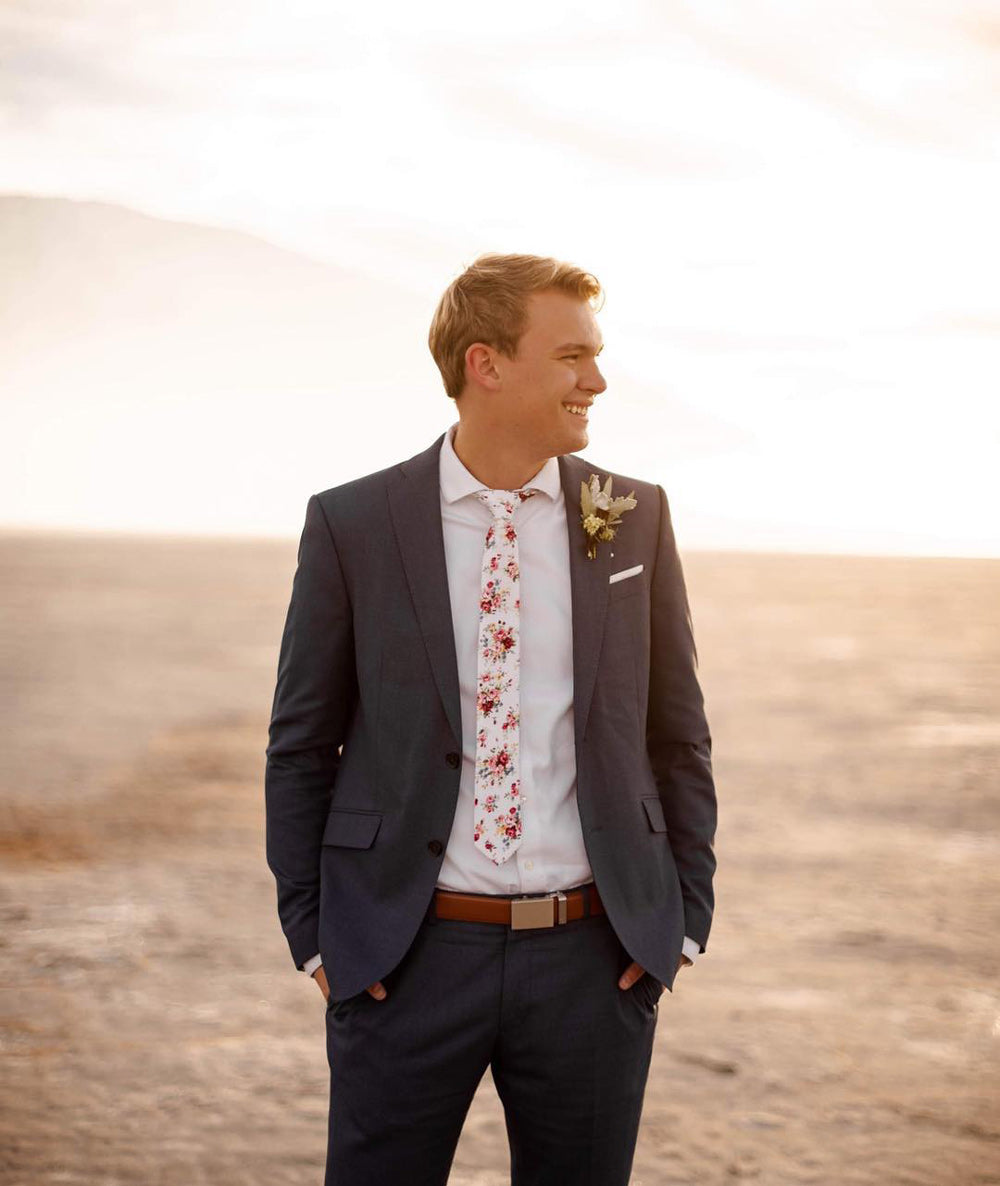 White Floral tie worn with a white shirt, brown belt and navy suit.