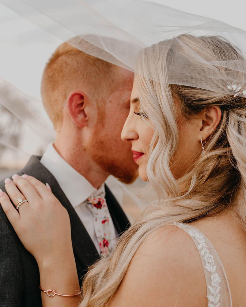 White Floral tie worn by groom at a wedding with a white shirt and dark gray suit jacket.